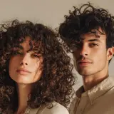 Ein Mann und eine Frau mit voluminösen Locken, die ihre Gesichter umrahmen. Ihre natürliche Locken-Routine zeigt sich in vollen, definierten Wellen.