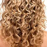 Ein Rücken mit vollem, blondem, krausem Haar, das in perfekten Locken fällt.