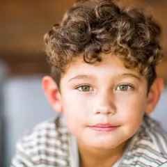 Ein Junge mit Locken, dessen Frisur an den "Lockenkopf" erinnert, schaut in die Kamera.