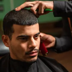 Mann bekommt einen Buzz Cut Low Fade beim Friseur. Die Haare werden kurz geschnitten, die Seiten verblassen sanft.