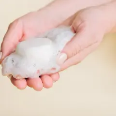 Hände halten festes Shampoo und Schaum. So einfach ist es, wie man festes Shampoo benutzt.