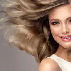 Ein Lächeln, das durch warmes blondes Haar umrahmt wird, das im Wind weht.