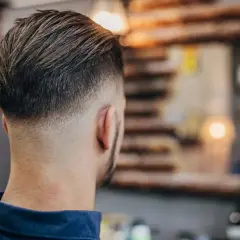 Mann mit modernem Fade-Haarschnitt, eine der angesagten herren frisuren. Der Übergang von kurz zu lang ist perfekt.