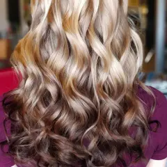 Langes, welliges Haar mit einem **Reverse Balayage**-Effekt, der von hellblond zu dunkleren Brauntönen übergeht.