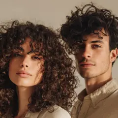 Ein Mann und eine Frau mit voluminösen Locken, die ihre Gesichter umrahmen. Ihre natürliche Locken-Routine zeigt sich in vollen, definierten Wellen.