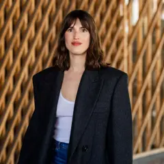 Frau mit braunem Haar und einem lässigen french crop, trägt einen Oversized-Blazer über einem weißen Top.