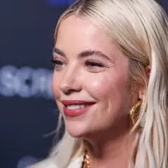 Lachende Frau mit blondem, gestuftem **long bob** und **seitenscheitel**. Goldene Creolen und Kette.
