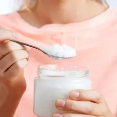 Eine Person hält einen Löffel mit Kokosfett, bereit für die Haarpflege.