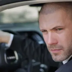 Mann mit Buzz Cut Mid Fade im Anzug fährt Auto.