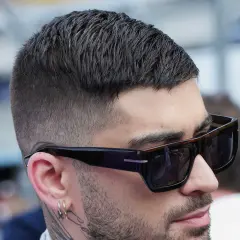 Mann mit stylischem herren kurzhaarschnitt, Sonnenbrille und Ohrringen.