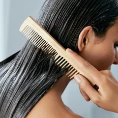 Frau kämmt nasses Haar mit Conditioner. Was ist Conditioner? Es macht das Haar weich und glänzend.