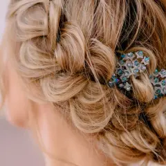 Zarte, geflochtene Strähnen und lockere Wellen ergeben eine elegante Hochsteckfrisur, verziert mit funkelnden Haarschmuck. Einfach und doch raffiniert.