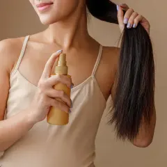 Frau sprüht sich Rosmarinwasser auf die Haare für mehr Glanz und Pflege.