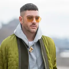 Mann mit French Crop High Fade, gelben Sonnenbrillen und Bomberjacke.