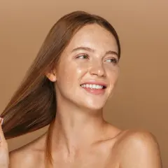 Frau mit Sommersprossen und glänzendem Haar, das wie von Birkenwasser gepflegt aussieht.