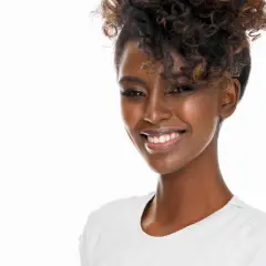 Lächelnde Frau mit voluminösen Locken, die sich für den perfekten Look Zeit nimmt, um Locken zu machen.