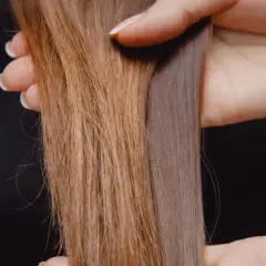 Hände halten zwei Strähnen lange Haare, eine braun, die andere grau-violett.
