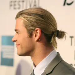 Jungs Frisur lang Surfer-Look: Blondes Haar zu einem kleinen Dutt gebunden, lässig und cool.