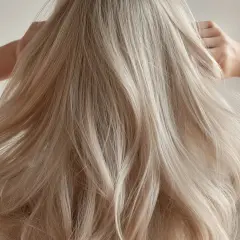 Blonde, dicke Haare fallen in Wellen über die Schultern. Eine Hand fährt durch das seidige Haar.