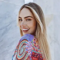 Frau mit Sommersprossen und einer **scandinavian hairline** lächelt in die Kamera, trägt ein buntes Kleid.