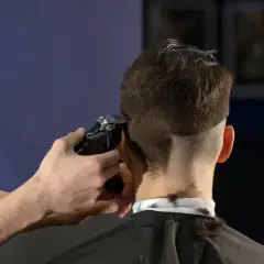 Friseur schneidet mit Maschine einen **mid fade** Haarschnitt.