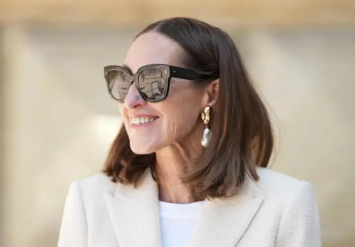 Stilvolle Frau mit mittellangem Haar, Sonnenbrille und auffälligem Ohrring. Perfekt für unkomplizierte Frisuren mittellang ab 50.