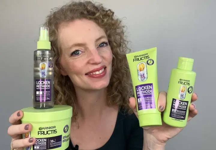 Frau mit lockigem Haar präsentiert die Garnier Fructis Locken Methode Produkte: Shampoo, Pre-Shampoo und Feuchtigkeits-Spray für definierte Locken.