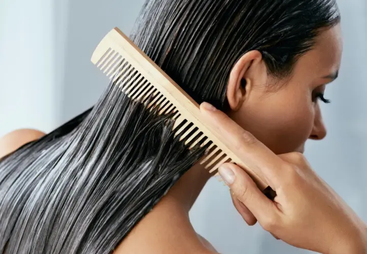 Frau kämmt nasses Haar mit Conditioner. Was ist Conditioner? Es macht das Haar weich und glänzend.