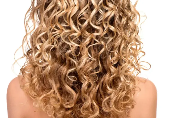 Ein Rücken mit vollem, blondem, krausem Haar, das in perfekten Locken fällt.