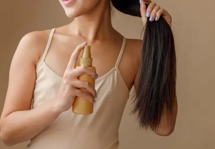 Frau sprüht sich Rosmarinwasser auf die Haare für mehr Glanz und Pflege.