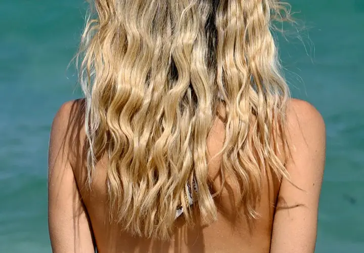 Lange, blonde Haare mit Beach Waves, die im Wind tanzen.