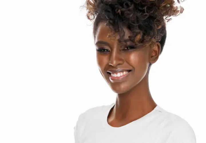 Lächelnde Frau mit voluminösen Locken, die sich für den perfekten Look Zeit nimmt, um Locken zu machen.