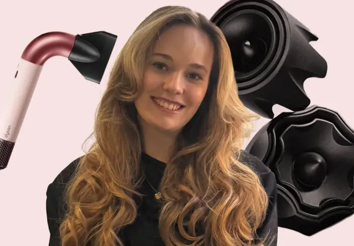 Lächelnde Frau mit voluminösen, welligen Haaren, die durch einen Dyson-Haartrockner und schwarze Aufsätze betont werden. Die Konturen der Haare sind perfekt gestylt.