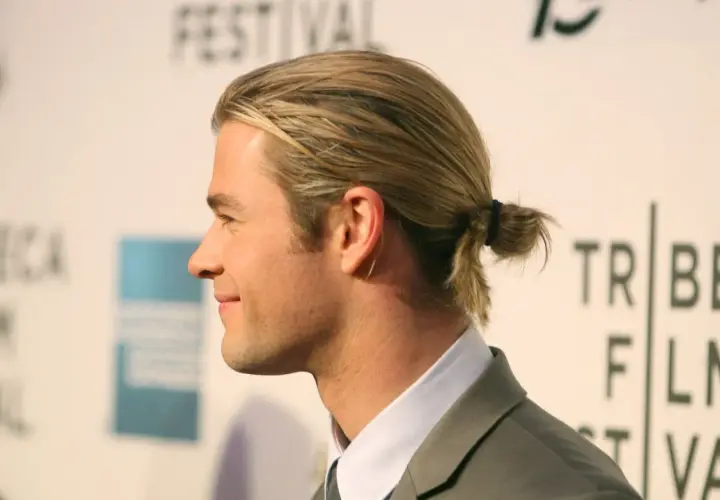 Jungs Frisur lang Surfer-Look: Blondes Haar zu einem kleinen Dutt gebunden, lässig und cool.
