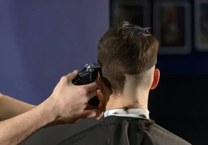Friseur schneidet mit Maschine einen **mid fade** Haarschnitt.