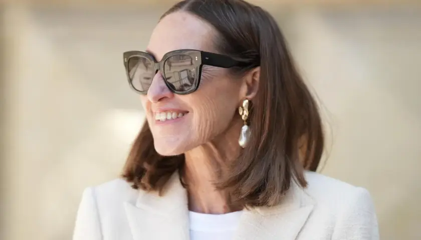 Stilvolle Frau mit mittellangem Haar, Sonnenbrille und auffälligem Ohrring. Perfekt für unkomplizierte Frisuren mittellang ab 50.