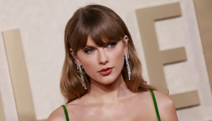 Taylor Swift mit ihrer charakteristischen hellbraunen taylor swift haarfarbe, funkelnden Ohrringen und einem grünen Kleid.