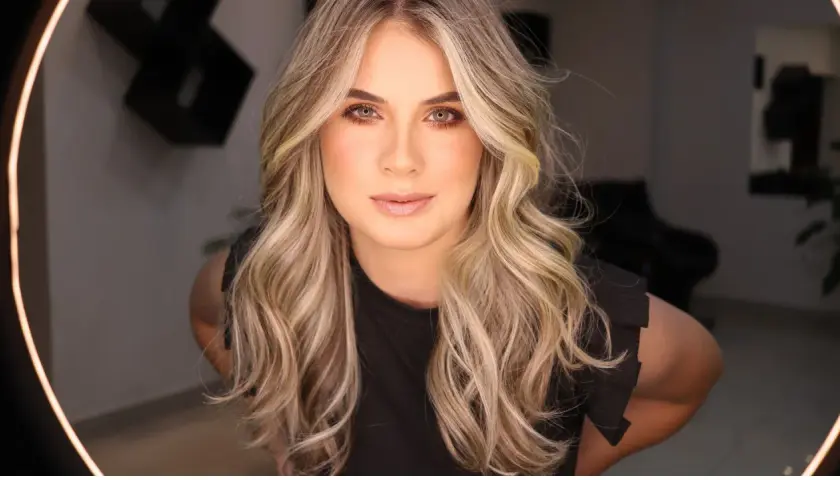 Blonde Frau mit welligem Haar, das ihr Gesicht umrahmt.