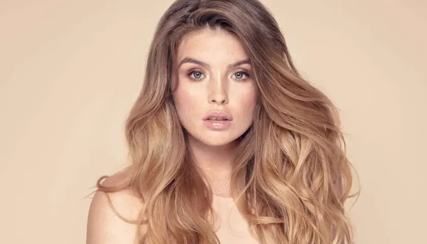 Frau mit vollem, welligem Haar und Sommersprossen. Sie träumt davon, dickere Haare zu bekommen, um diesen Look zu erzielen.