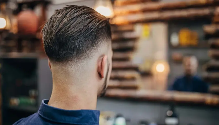 Mann mit modernem Fade-Haarschnitt, eine der angesagten herren frisuren. Der Übergang von kurz zu lang ist perfekt.