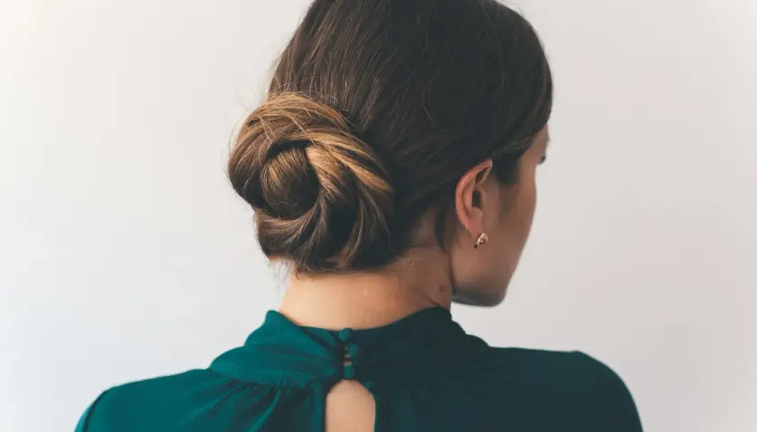 Eine Frau mit einem eleganten Dutt, der ihr Haar kunstvoll zusammenhält.