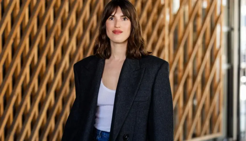 Frau mit braunem Haar und einem lässigen french crop, trägt einen Oversized-Blazer über einem weißen Top.