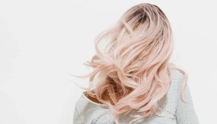 Eine Person mit langen, welligen, rosafarbenen Haaren. Die Haarfarben mischen Tabelle könnte hier inspirieren.
