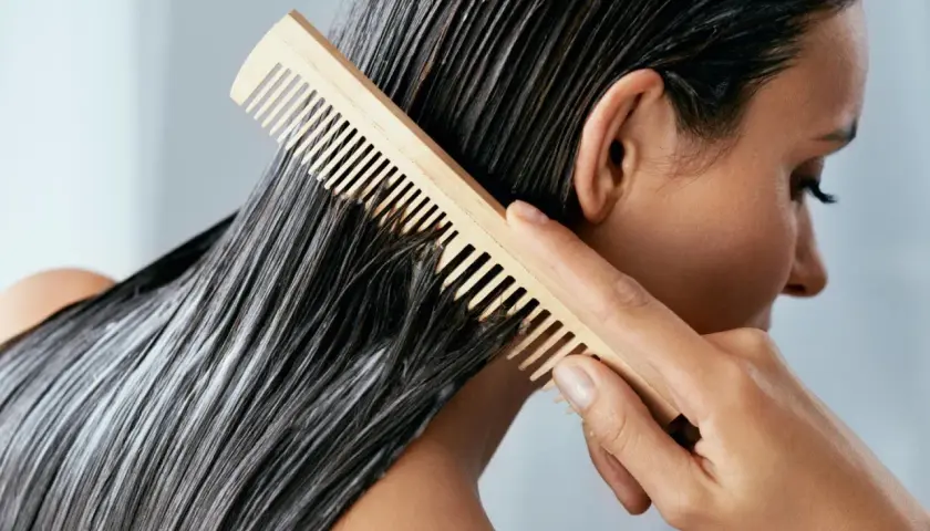 Frau kämmt nasses Haar mit Conditioner. Was ist Conditioner? Es macht das Haar weich und glänzend.