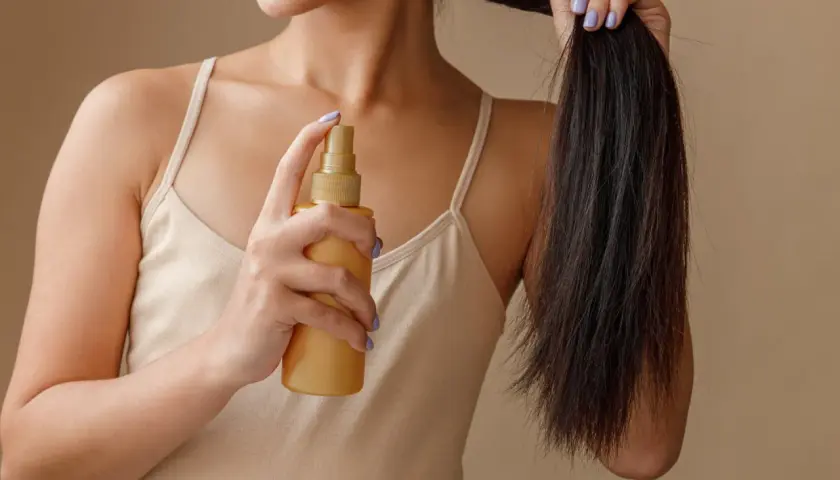 Frau sprüht sich Rosmarinwasser auf die Haare für mehr Glanz und Pflege.