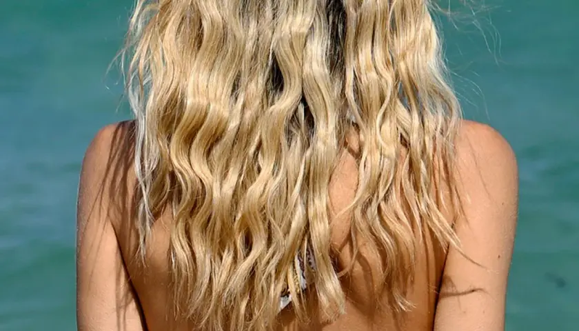 Lange, blonde Haare mit Beach Waves, die im Wind tanzen.