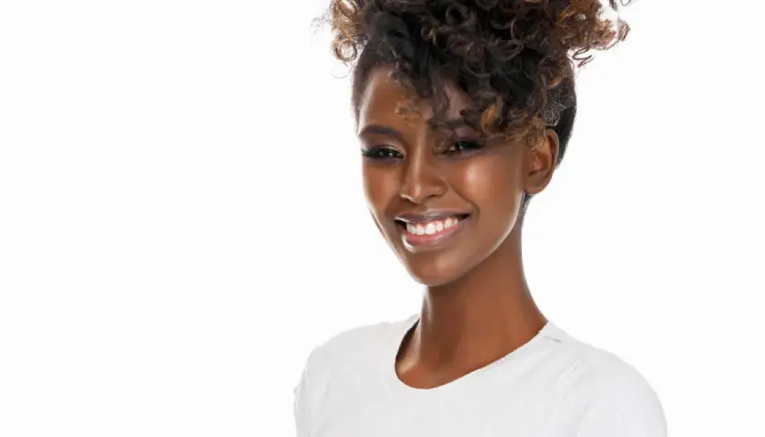 Lächelnde Frau mit voluminösen Locken, die sich für den perfekten Look Zeit nimmt, um Locken zu machen.