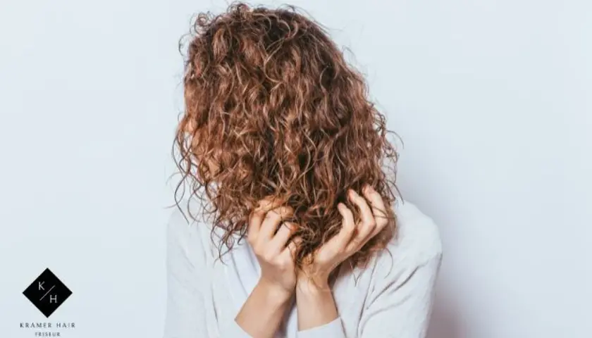 Frauen mit einer voluminösen Dauerwelle, die ihre Hände durch die Locken gleiten lassen.