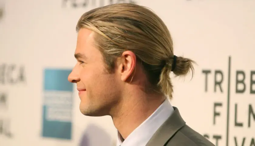 Jungs Frisur lang Surfer-Look: Blondes Haar zu einem kleinen Dutt gebunden, lässig und cool.