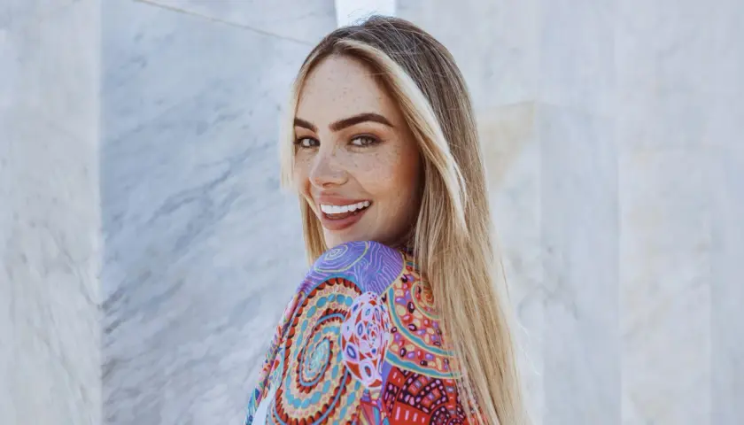 Frau mit Sommersprossen und einer **scandinavian hairline** lächelt in die Kamera, trägt ein buntes Kleid.